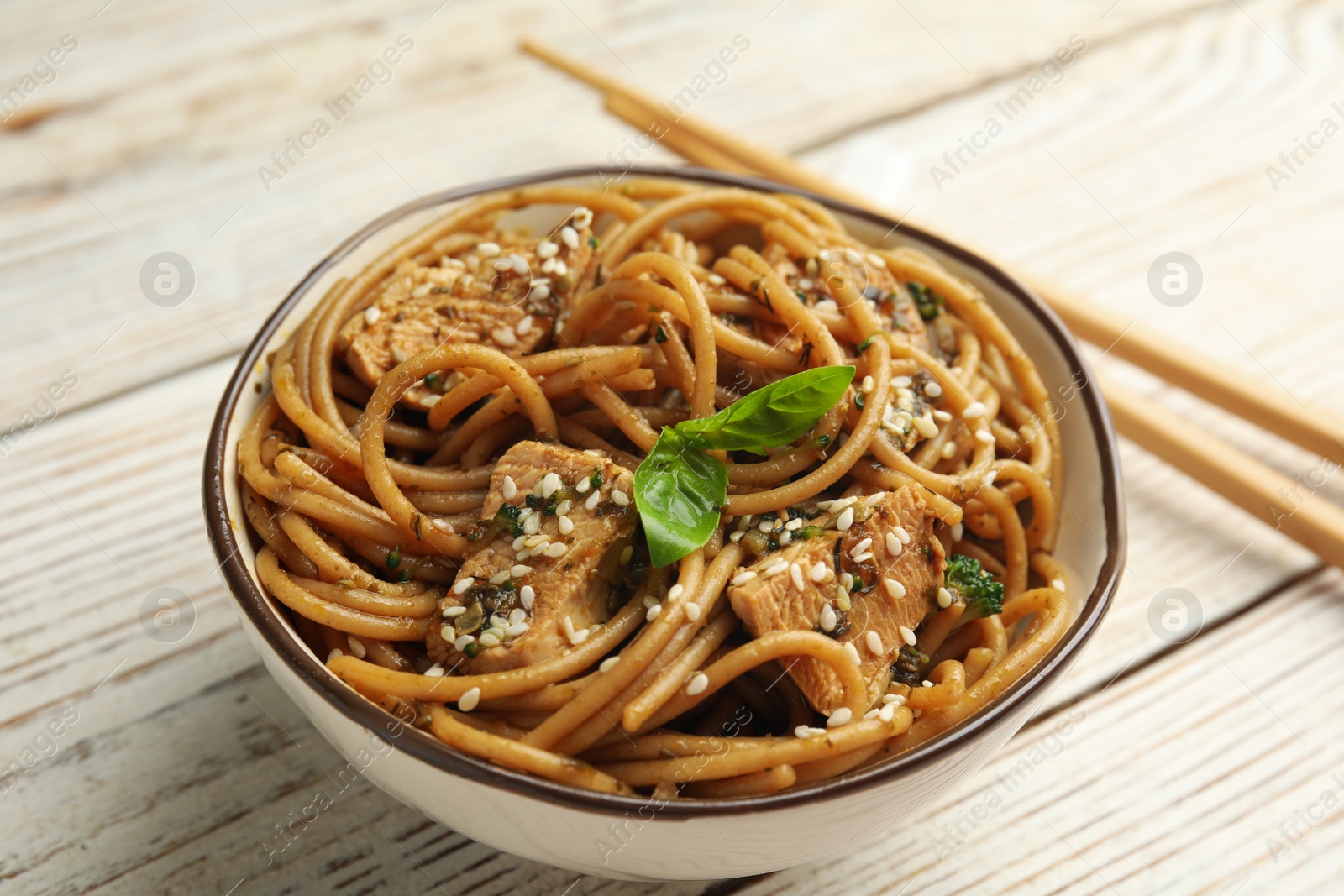 Photo of Tasty buckwheat noodles with meat in bowl on white wooden table