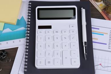 Photo of Calculator, papers, pen, notebook on wooden table, above view. Pension planning