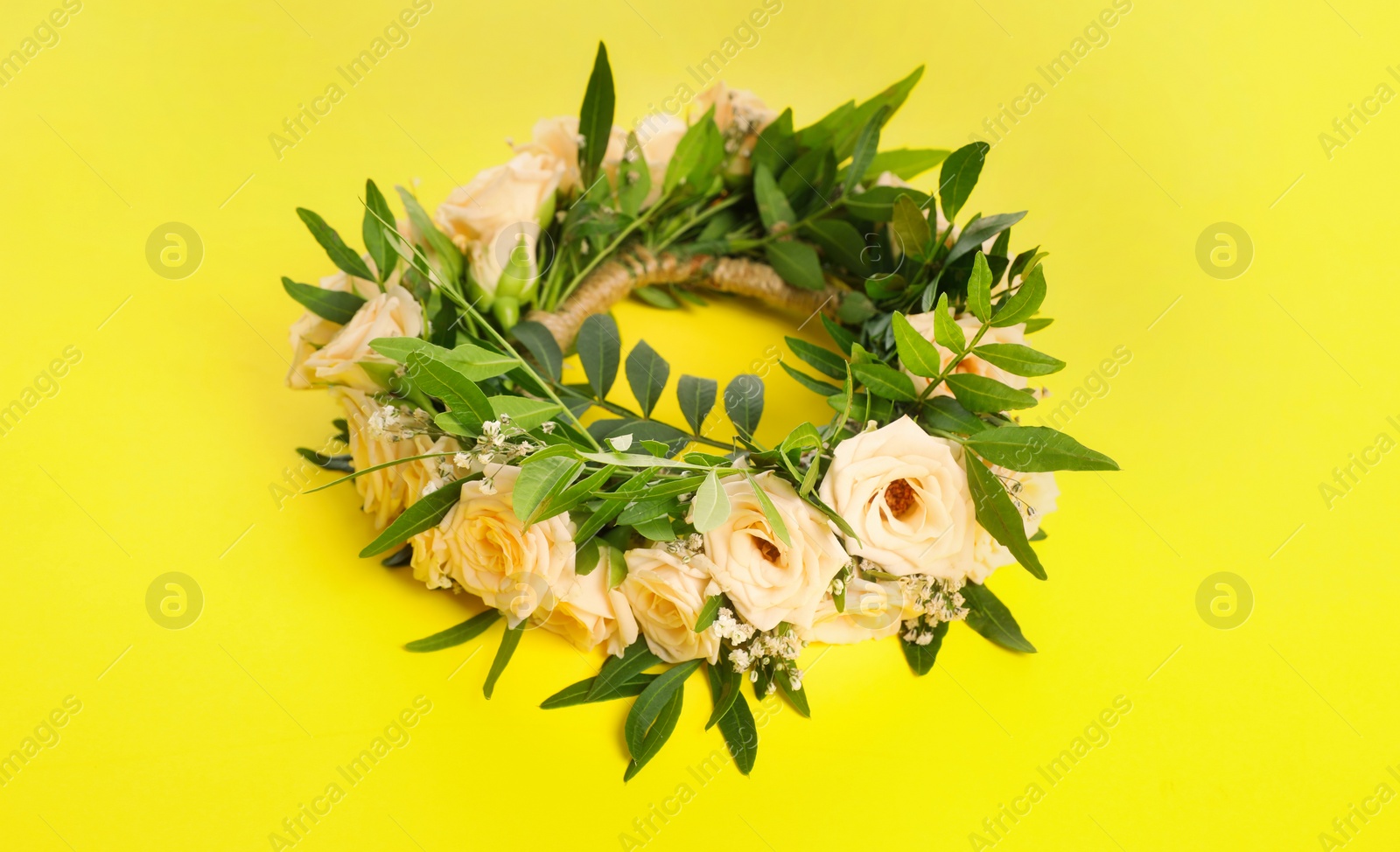 Photo of Wreath made of beautiful flowers on yellow background
