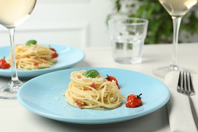 Tasty spaghetti with tomatoes and cheese served on white wooden table, closeup. Exquisite presentation of pasta dish