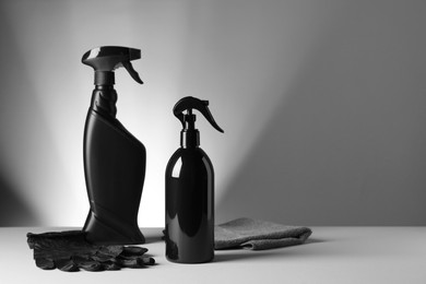 Spray bottles, black gloves and rag on white table. Car products