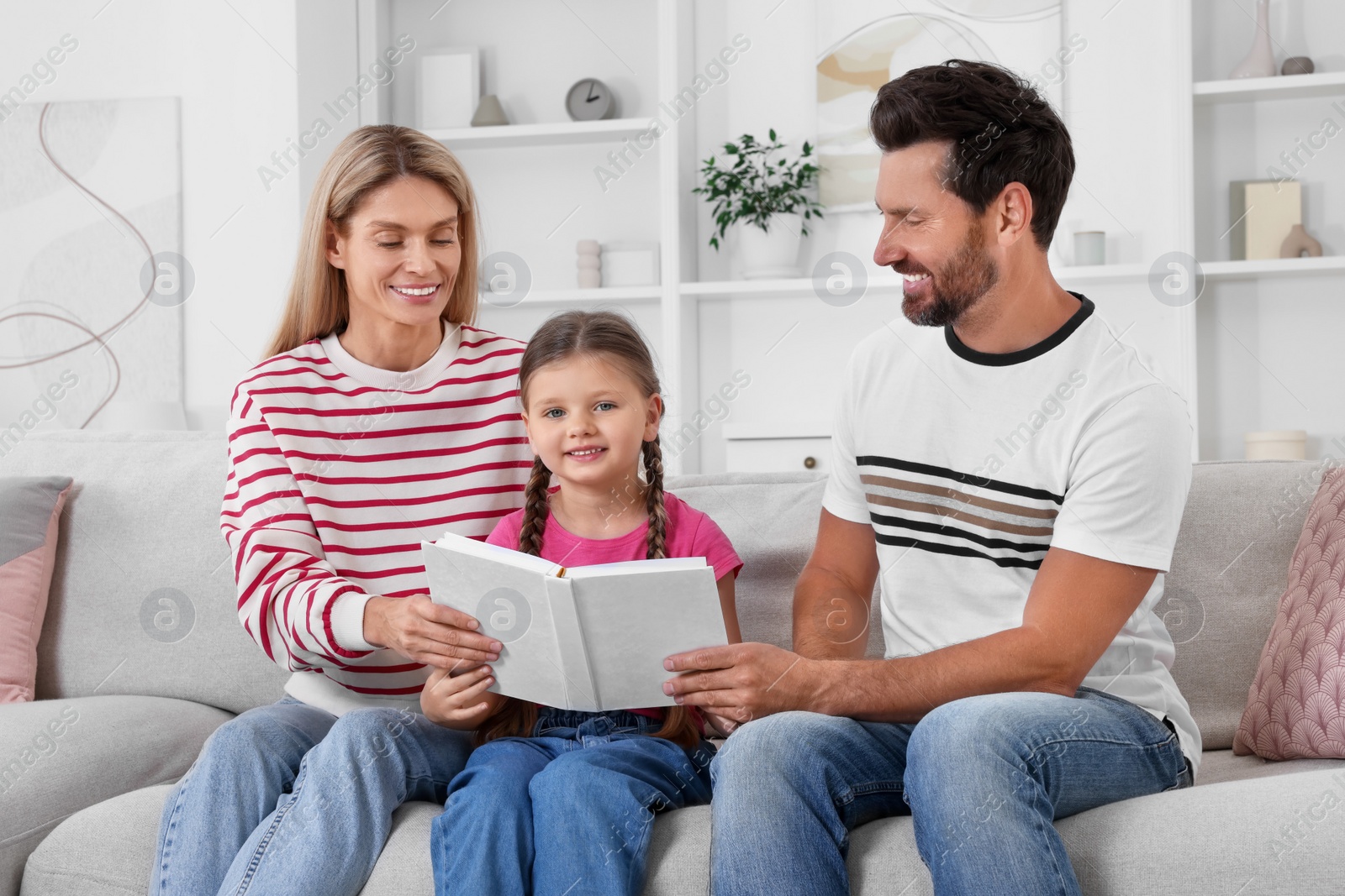 Photo of Happy family reading book together on sofa at home