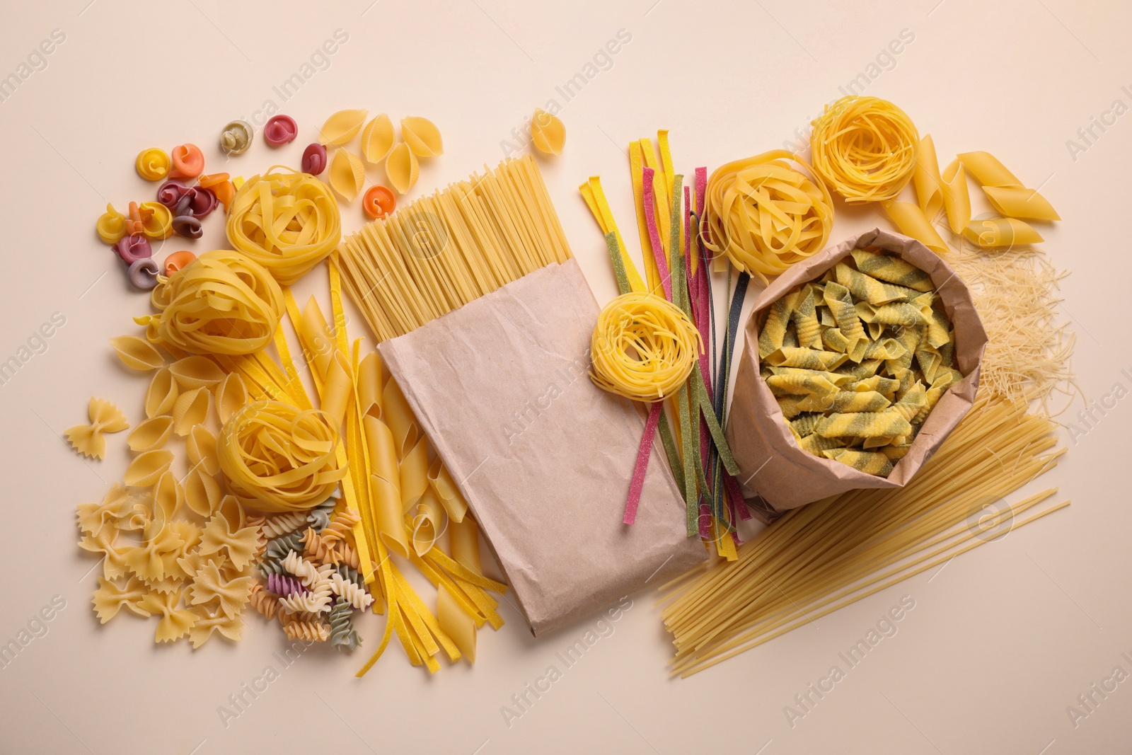 Photo of Different types of pasta on beige background, flat lay