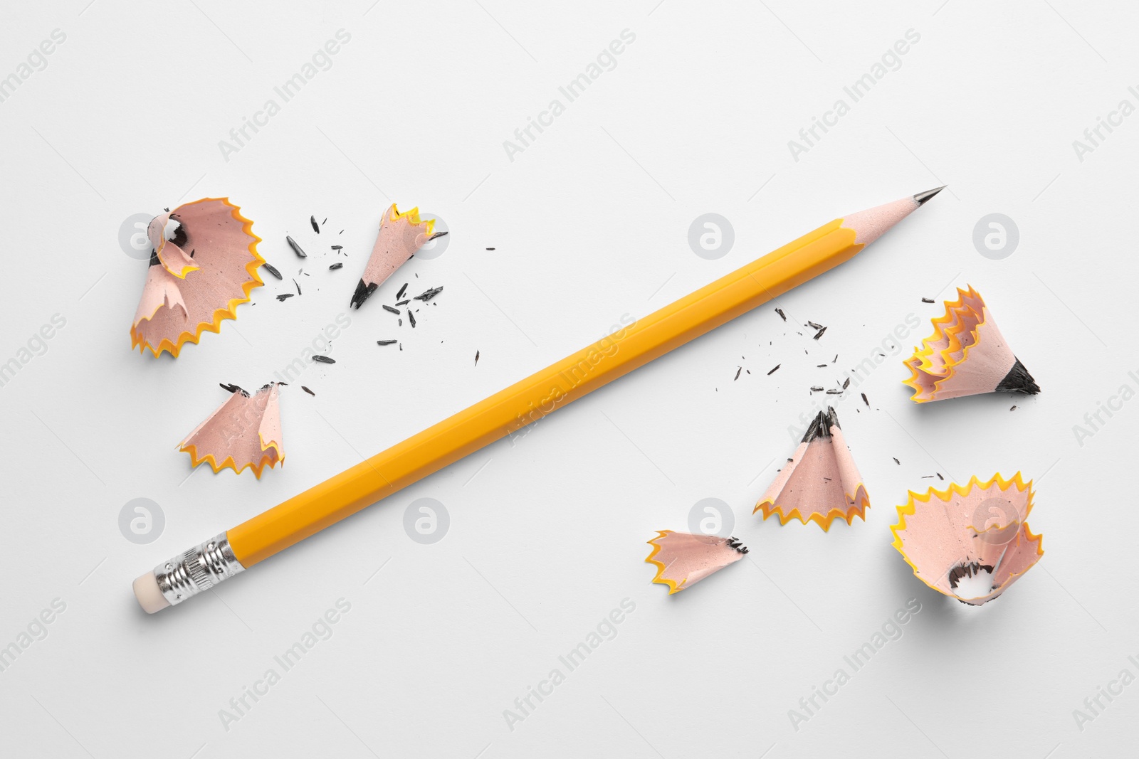 Photo of Graphite pencil and shavings on white background, flat lay