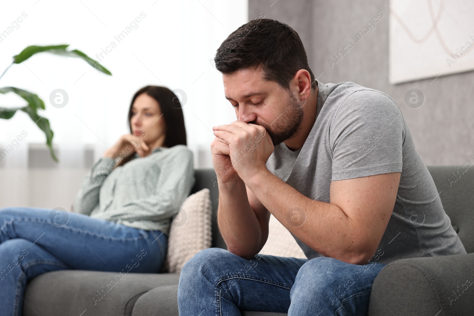 Photo of Offended couple ignoring each other after quarrel indoors, selective focus. Relationship problems