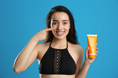 Photo of Young woman with sun protection cream on blue background