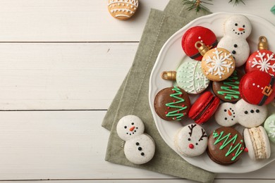 Photo of Beautifully decorated Christmas macarons on white wooden table, flat lay. Space for text