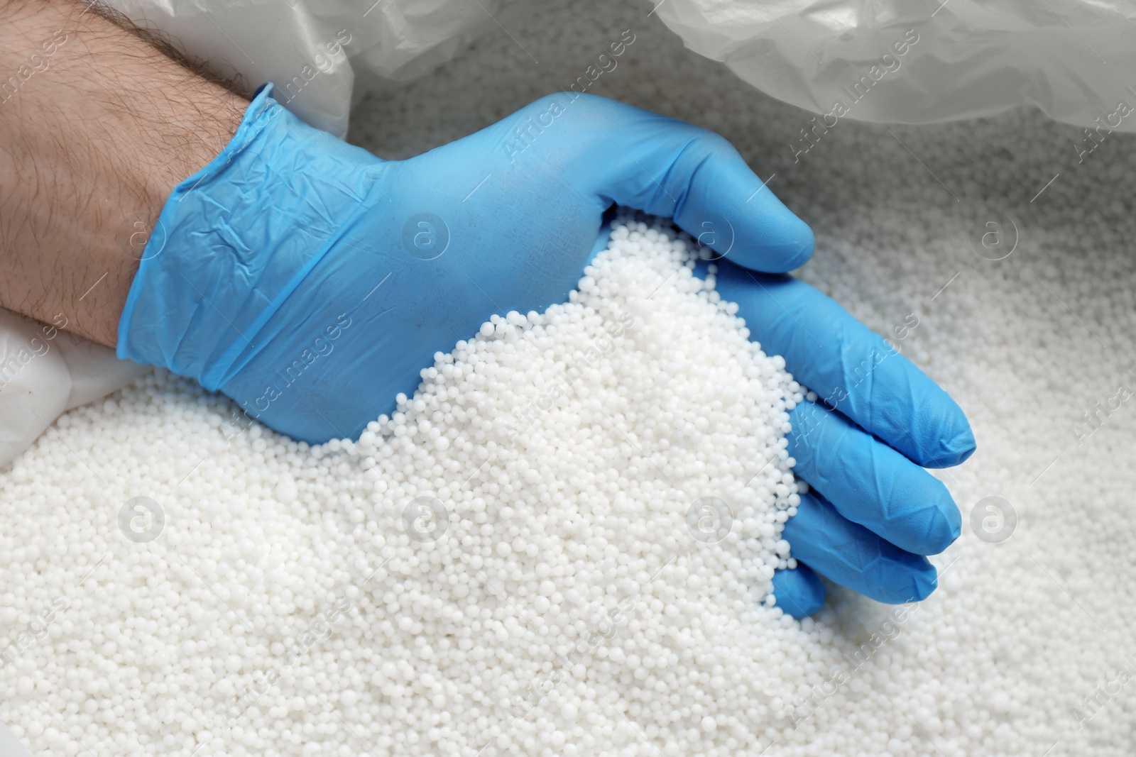 Photo of Person in gloves taking pellets of ammonium nitrate from bag, closeup. Mineral fertilizer