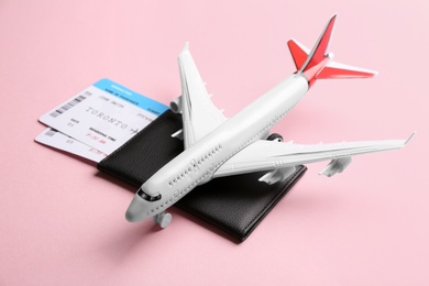 Photo of Toy airplane and passport with tickets on pink background