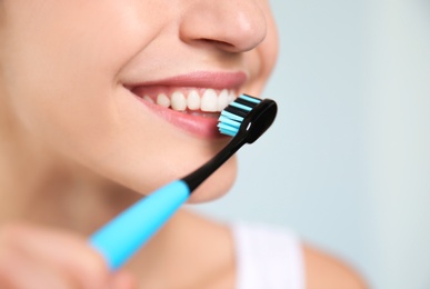 Young woman with toothbrush on blurred background, closeup. Space for text