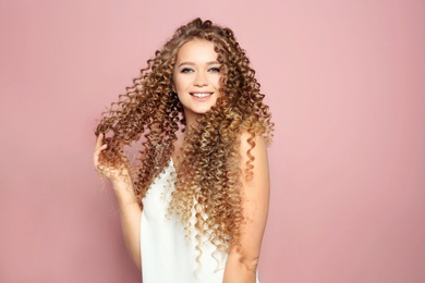 Portrait of beautiful young woman with shiny wavy hair on color background