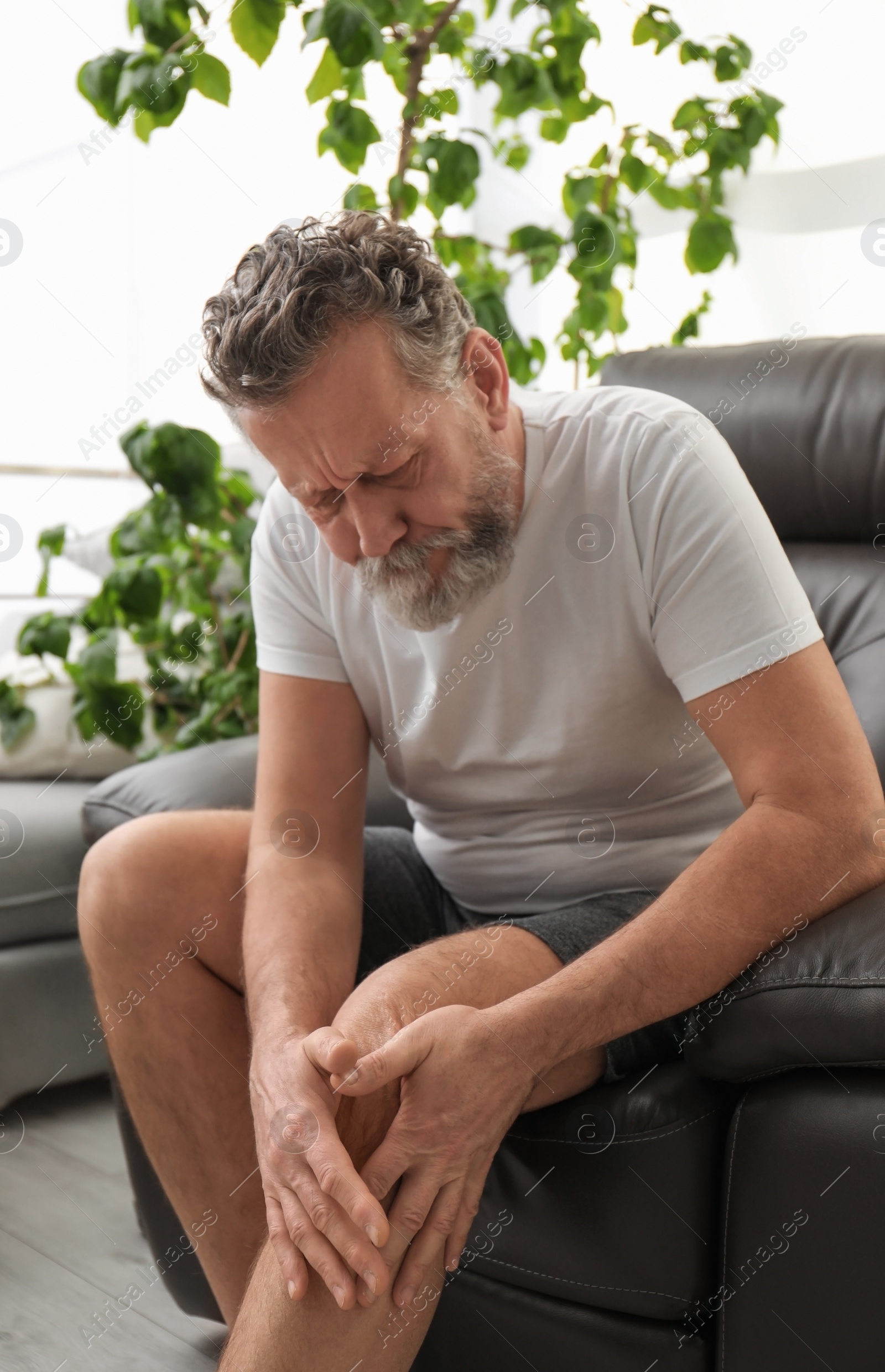 Photo of Senior man suffering from knee pain indoors