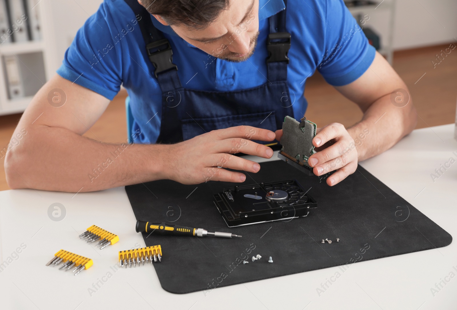 Photo of Male technician repairing hard drive at table indoors, closeup