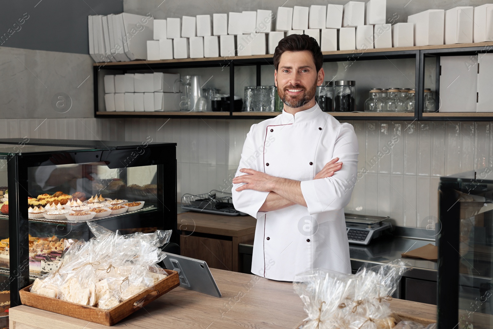 Photo of Professional baker at cashier desk near showcase in store