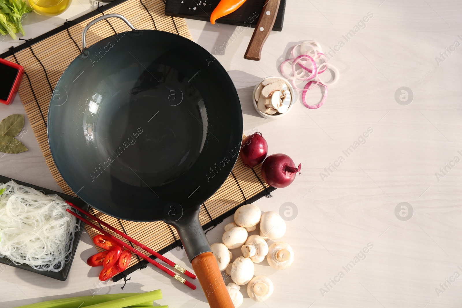 Photo of Wok, chopsticks and different products on white wooden table, flat lay. Space for text