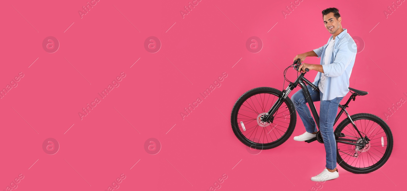 Image of Handsome young man with modern bicycle on pink background, space for text. Banner design