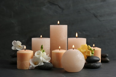 Composition of burning candles, spa stones and flowers on table