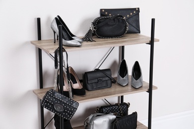 Photo of Shelving unit with stylish shoes and purses near white wall. Element of dressing room interior