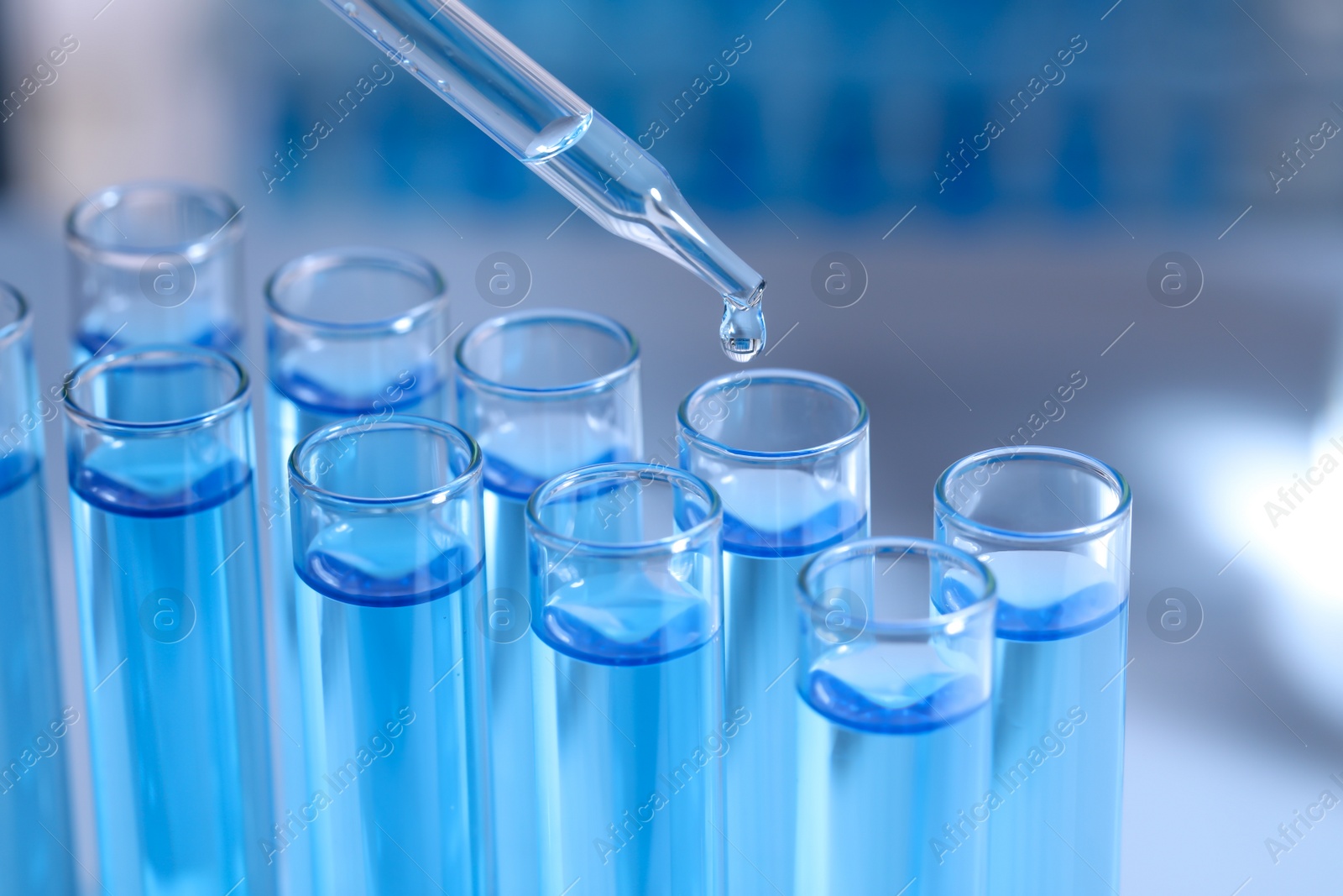 Photo of Dripping reagent into test tube on blurred background, closeup. Laboratory analysis