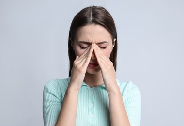 Photo of Young woman suffering from headache on light background