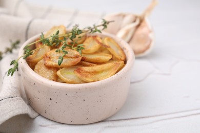 Photo of Fried garlic cloves and thyme in bowl on white table, closeup. Space for text