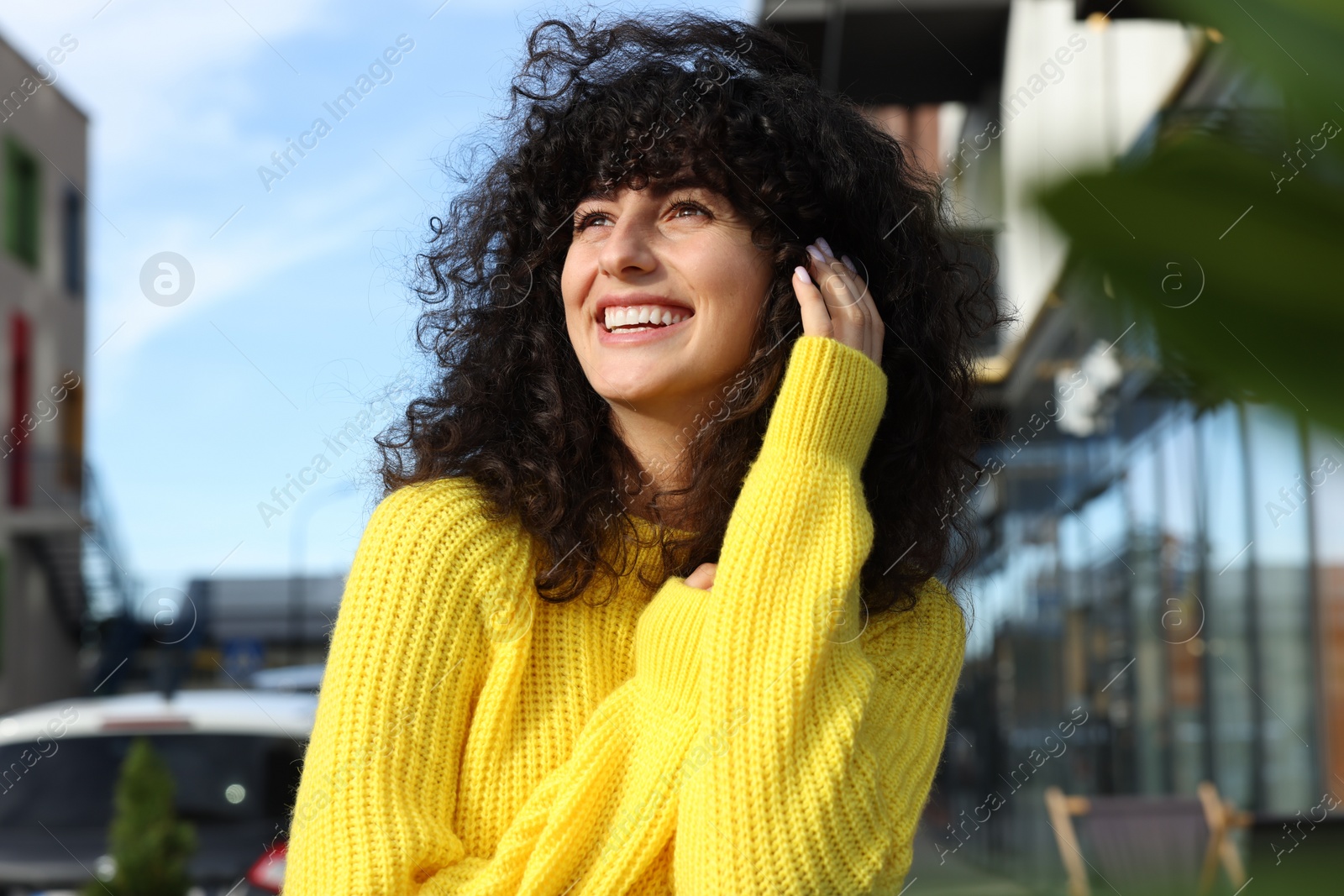 Photo of Happy young woman in stylish yellow sweater outdoors