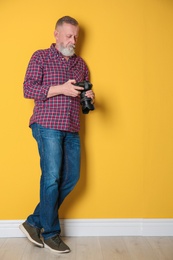 Mature male photographer with camera  near color wall