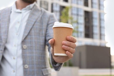 Photo of Coffee to go. Man with paper cup of drink outdoors, selective focus. Space for text