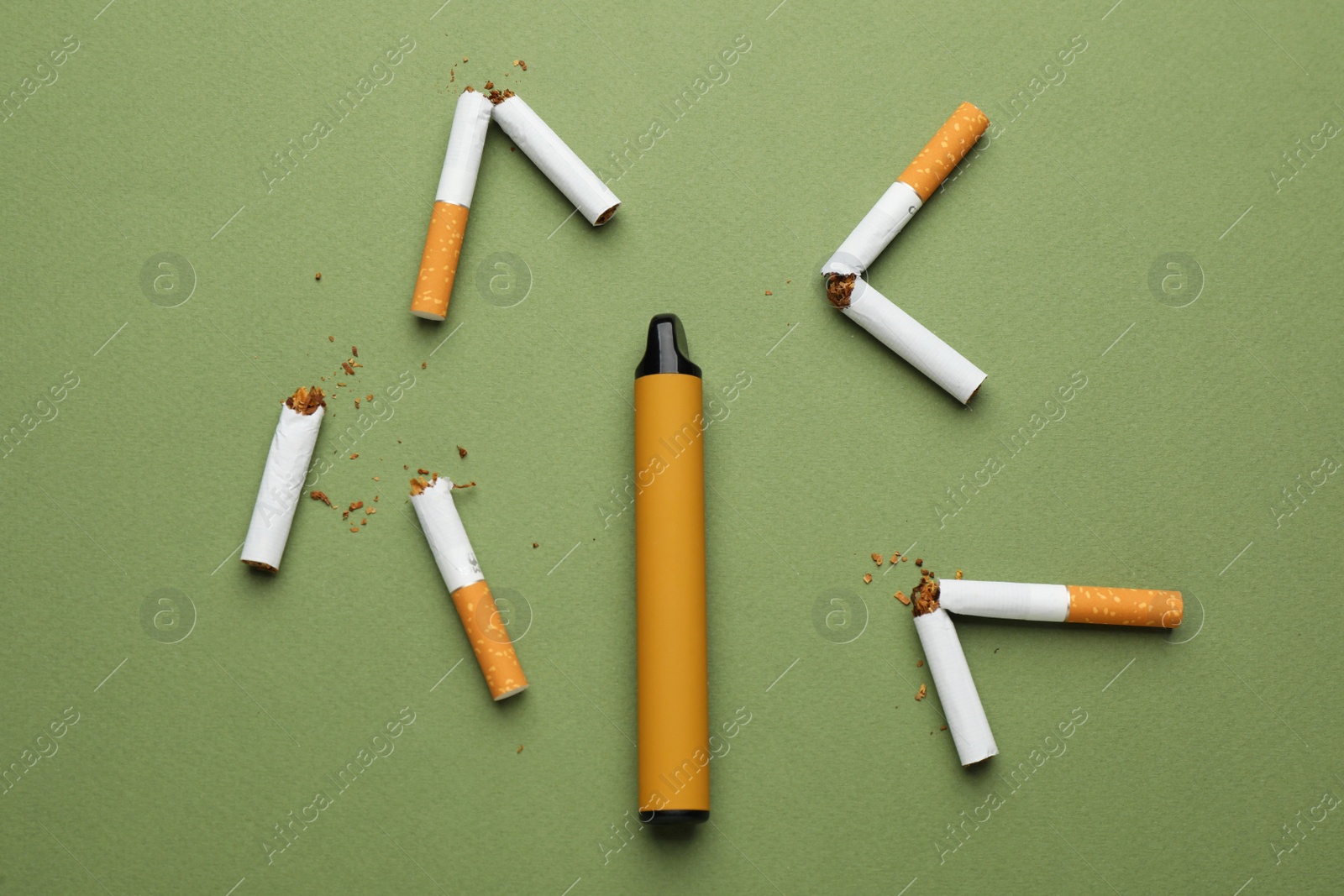 Photo of Disposable electronic smoking device surrounded by broken cigarettes on olive background, flat lay