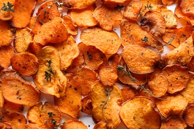 Sweet potato chips with herbs on white background, top view