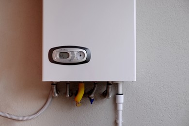 Photo of Gas boiler with temperature control indicator on white wall