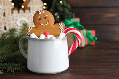Photo of Gingerbread man in cup on wooden table