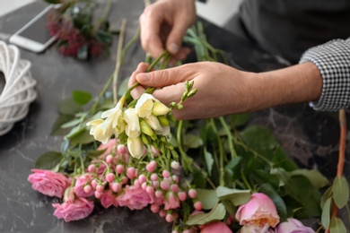 Male florist creating beautiful bouquet at table, closeup