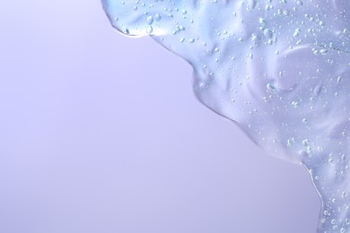 Photo of Transparent cleansing gel on violet background, top view with space for text. Cosmetic product