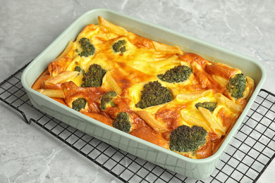 Photo of Tasty broccoli casserole in baking dish on cooling rack