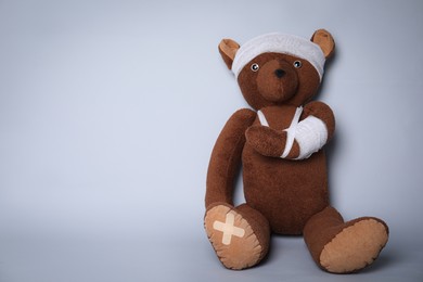 Photo of Toy bear with bandages on light grey background. Space for text
