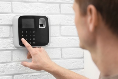 Photo of Man using security alarm system indoors, closeup