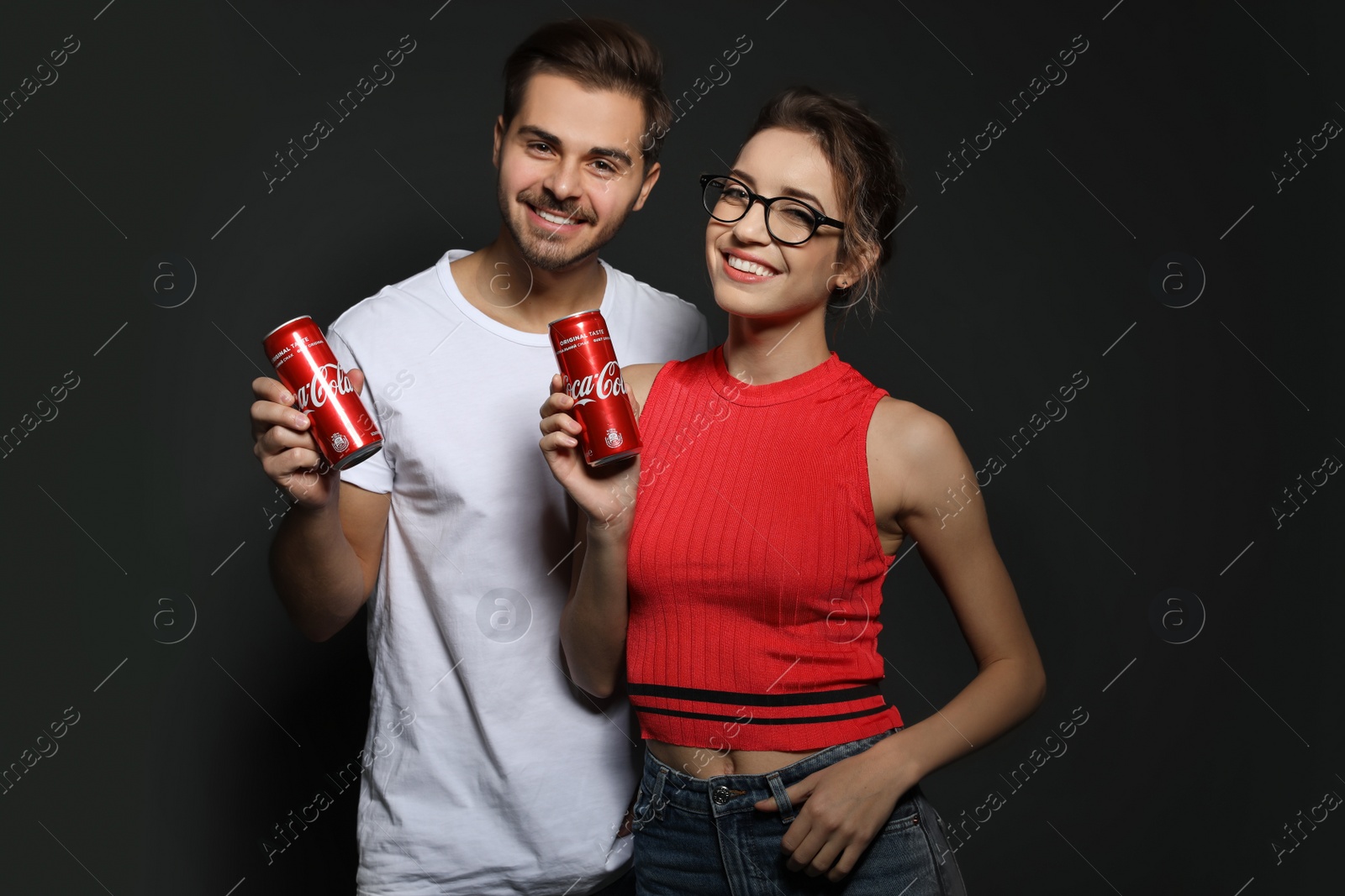 Photo of MYKOLAIV, UKRAINE - NOVEMBER 28, 2018: Young couple with Coca-Cola cans on dark background