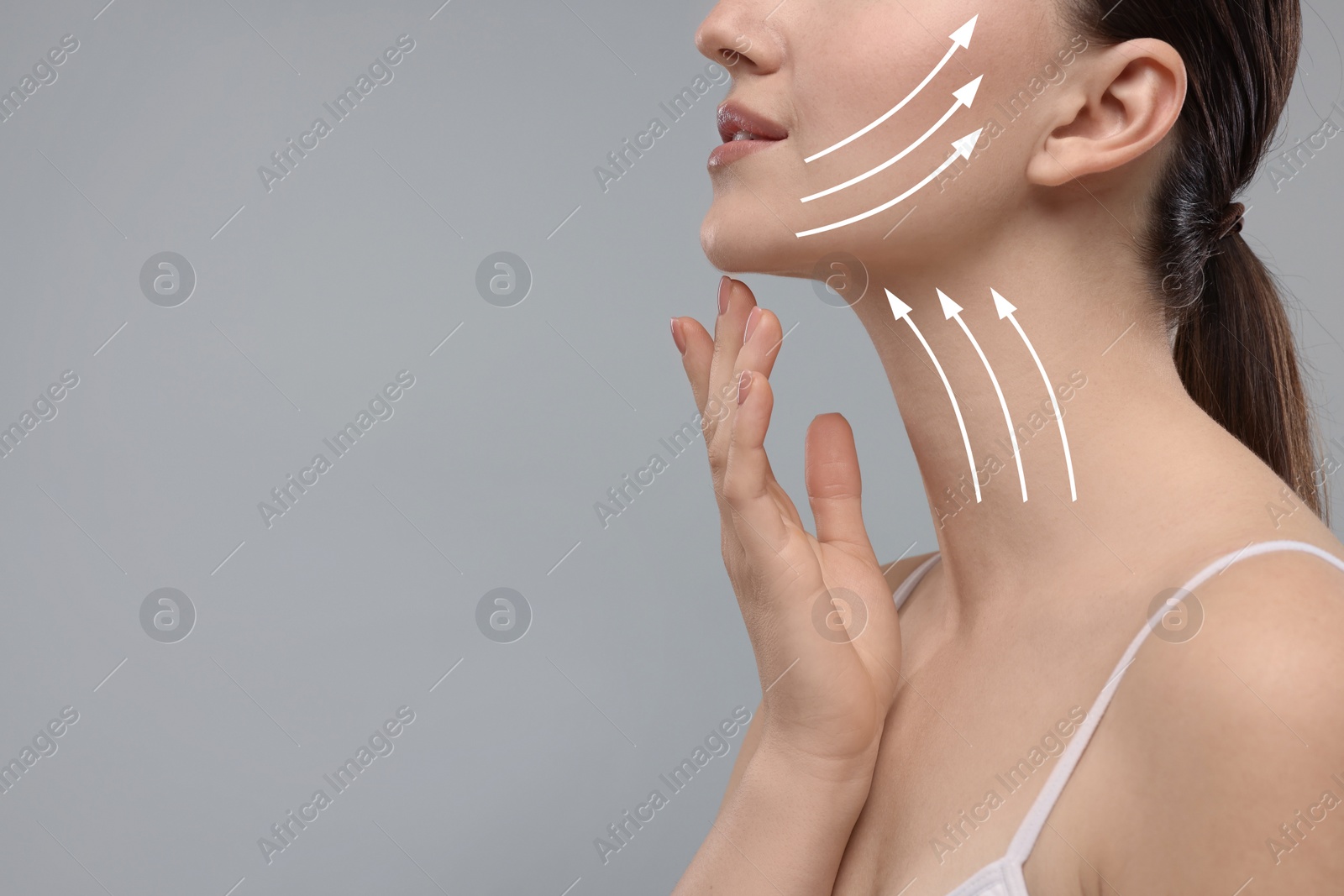 Image of Woman with perfect skin after cosmetic treatment on grey background, space for text. Lifting arrows on her neck and face