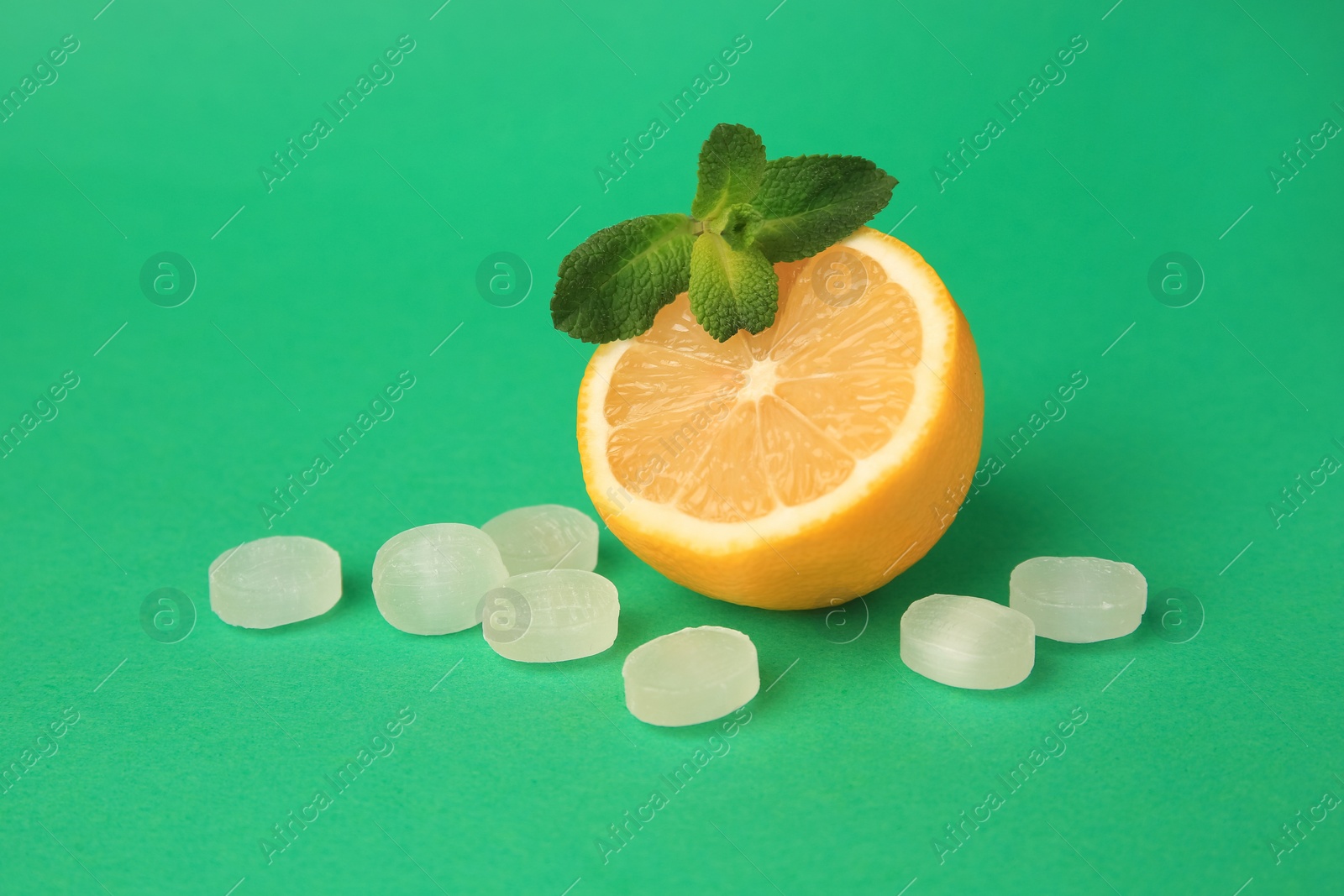Photo of Fresh lemon, mint leaves and cough drops on green background