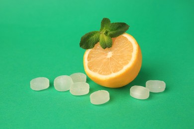 Fresh lemon, mint leaves and cough drops on green background