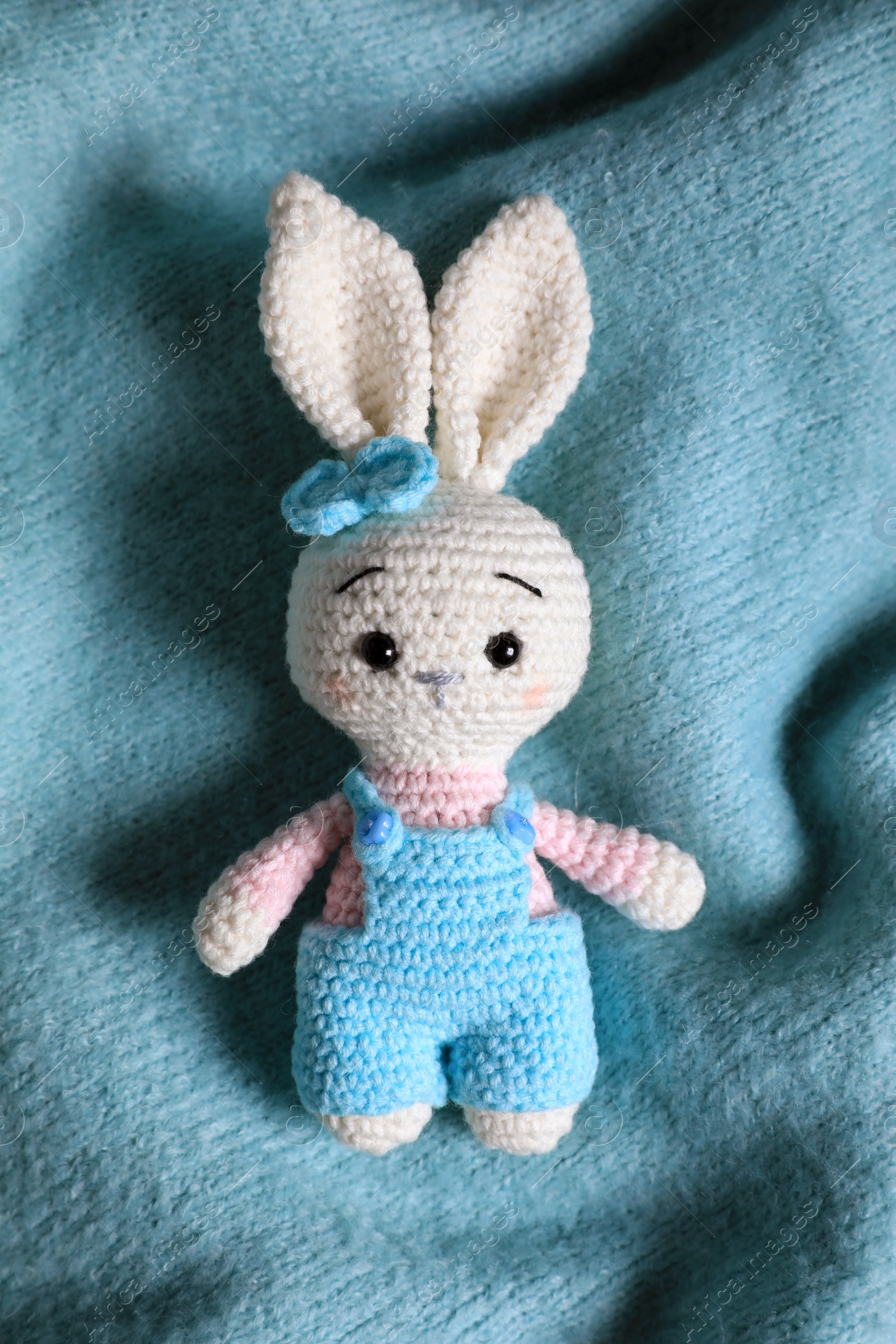 Photo of Adorable white toy bunny on turquoise fabric