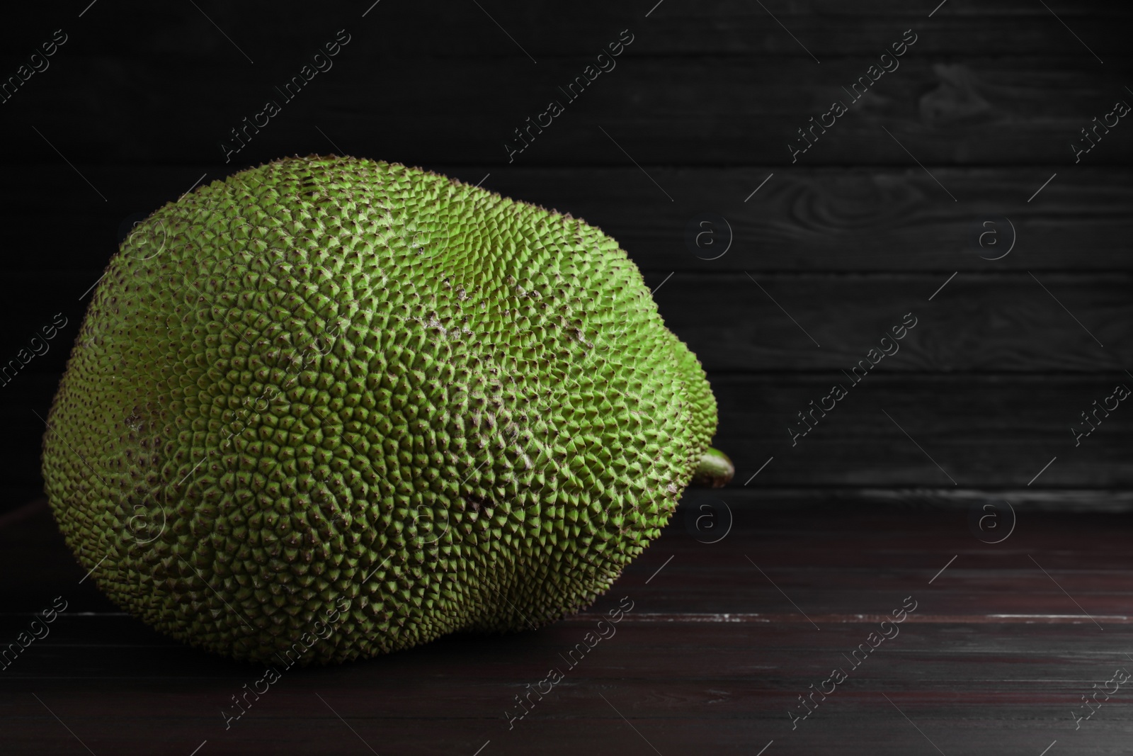 Photo of Fresh exotic jackfruit on black wooden table. Space for text