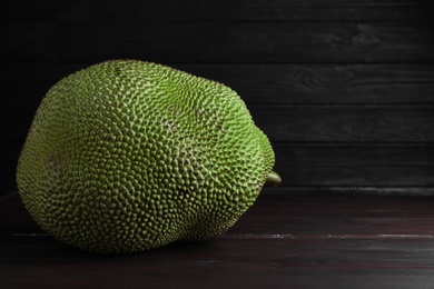 Photo of Fresh exotic jackfruit on black wooden table. Space for text