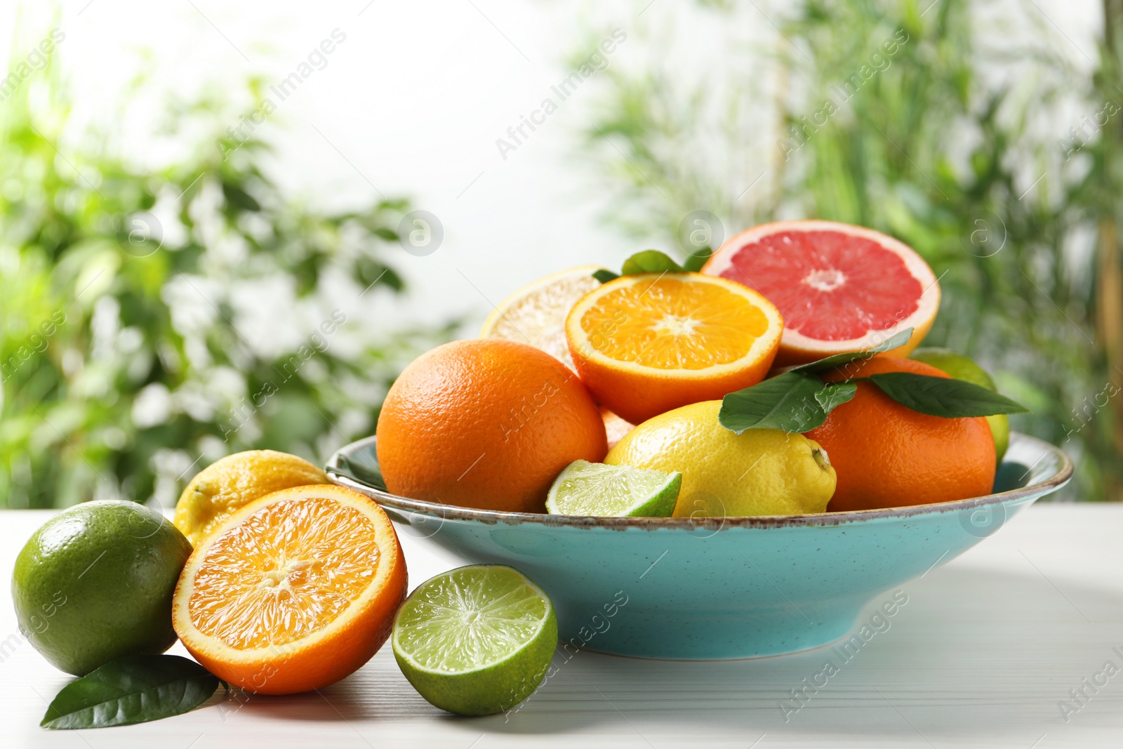 Photo of Different cut and whole citrus fruits on white wooden table outdoors