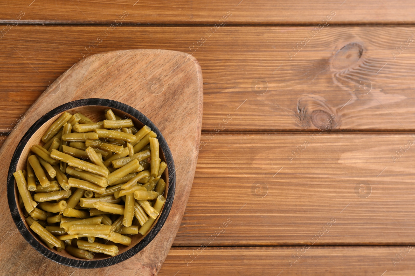 Photo of Canned green beans on wooden table, top view. Space for text