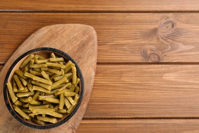 Canned green beans on wooden table, top view. Space for text