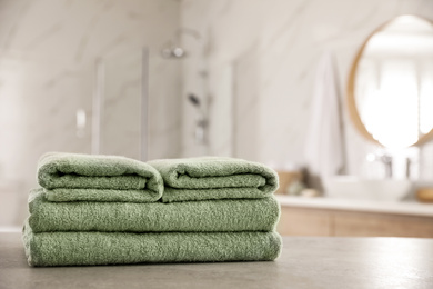 Stack of clean towels on table in bathroom