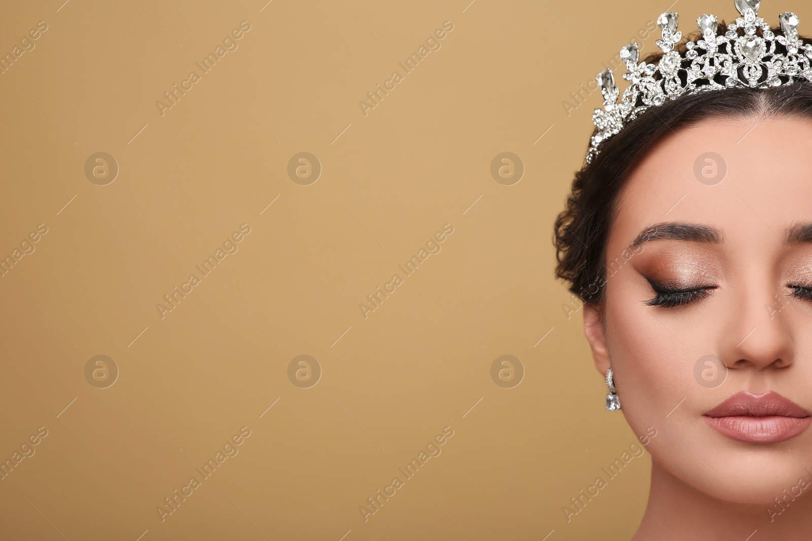 Photo of Beautiful young woman wearing luxurious tiara on beige background, closeup. Space for text