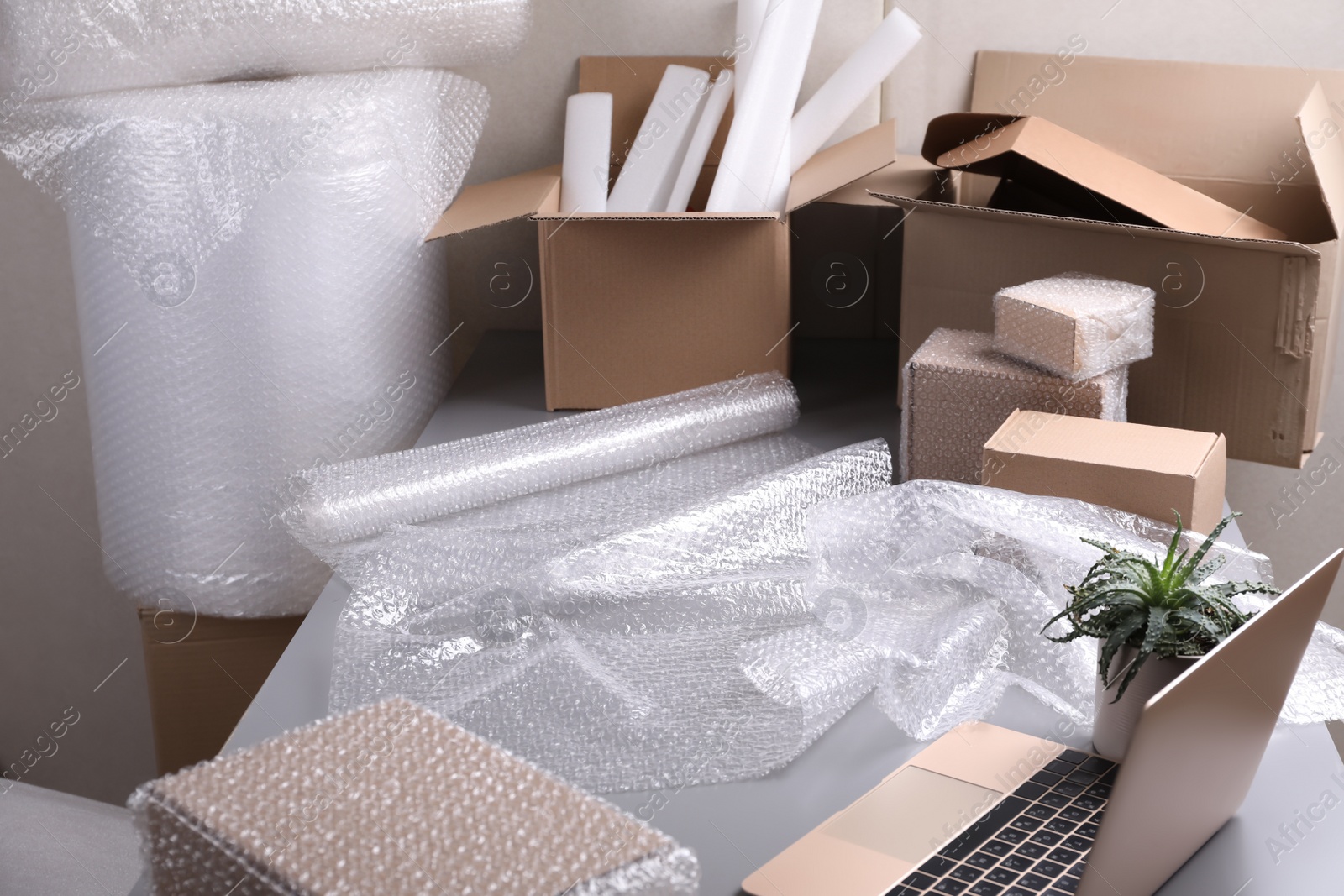 Photo of Table with laptop, boxes and bubble wrap in warehouse